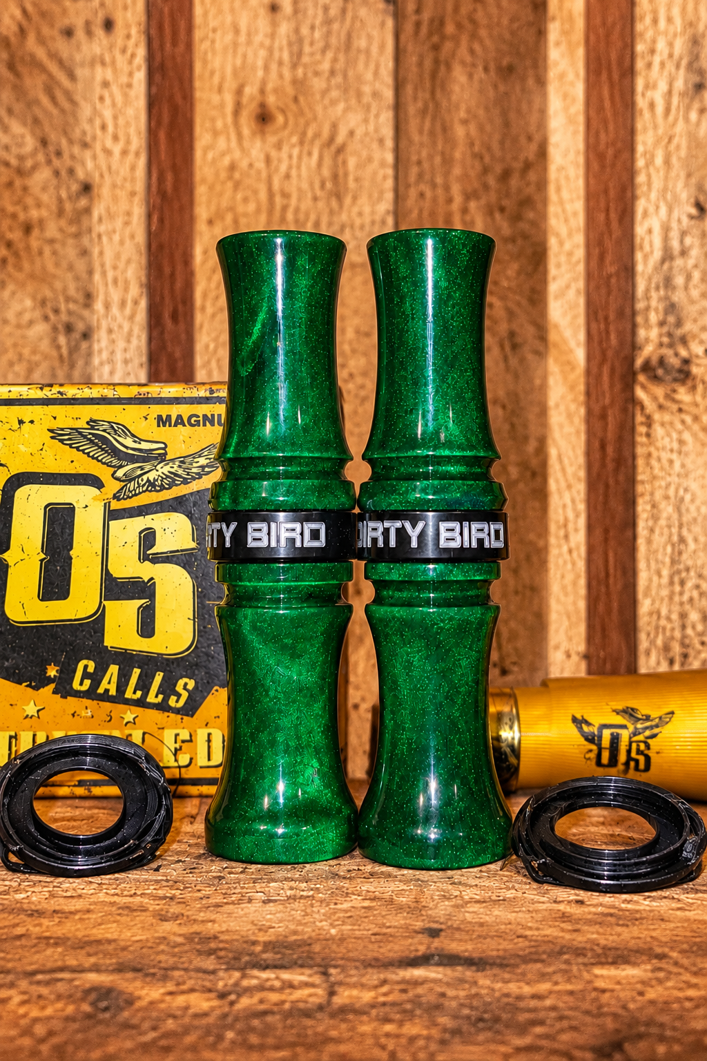 Two green glitter birdshot blasters with black bands labeled 'DIRTY BIRD' on a wooden surface.